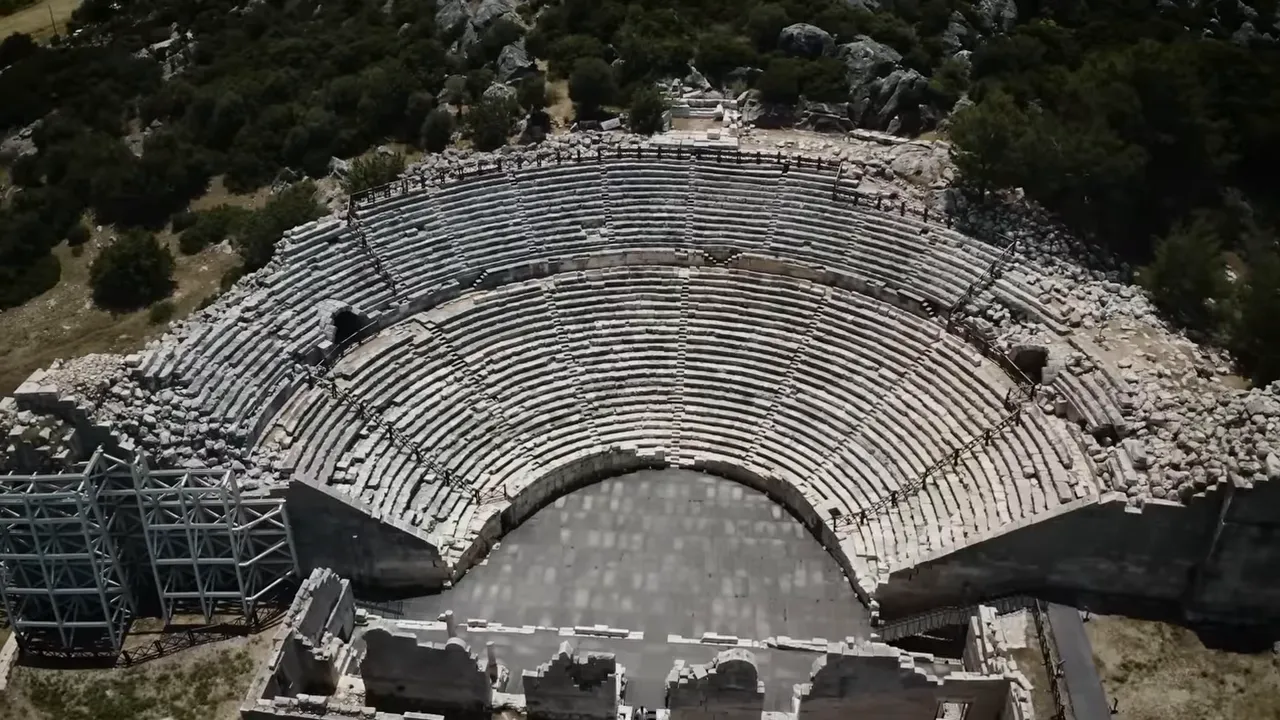 Bird's-eye aerial view of the ancient Patara theatre showing the full semicircular seating and stage area.