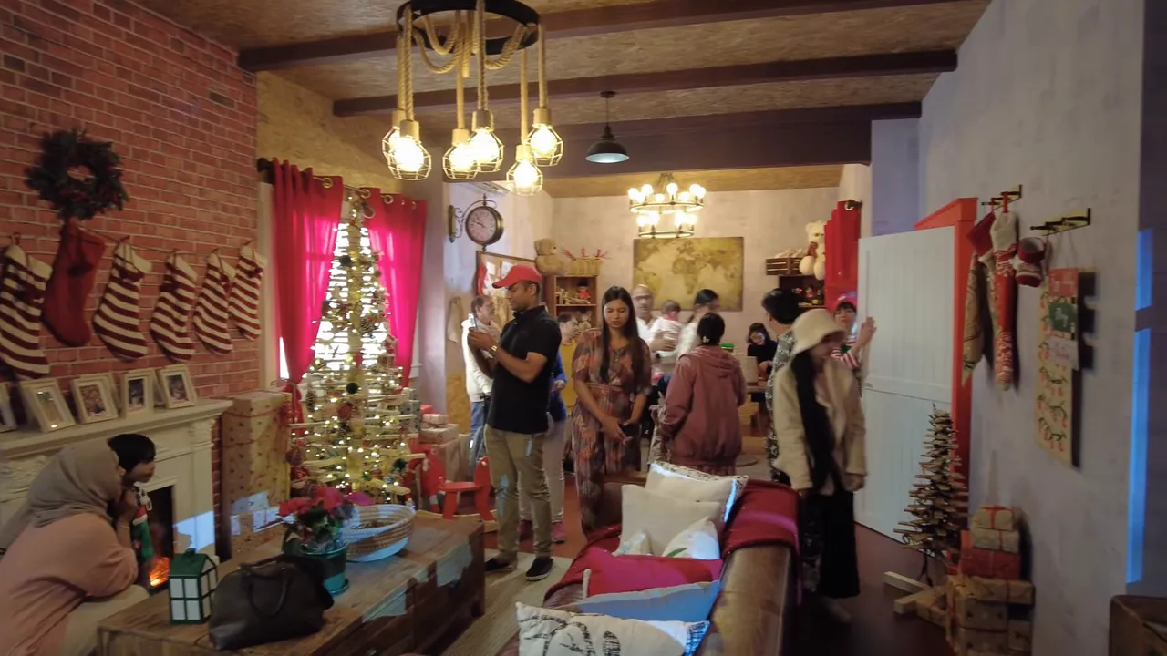 Cozy interior corner at Winter City with a decorated Christmas tree, stockings, warm pendant lights and visitors