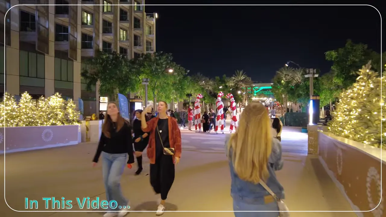 Night walkway at Expo City Winter City with illuminated trees, candy‑cane decorations and visitors strolling.