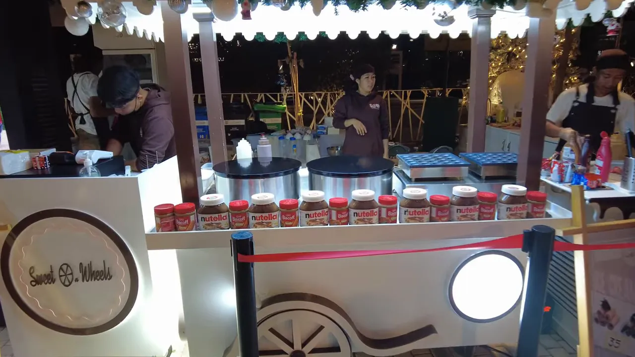 dessert stall lined with Nutella jars, crepe griddles and staff preparing treats at Winter City market