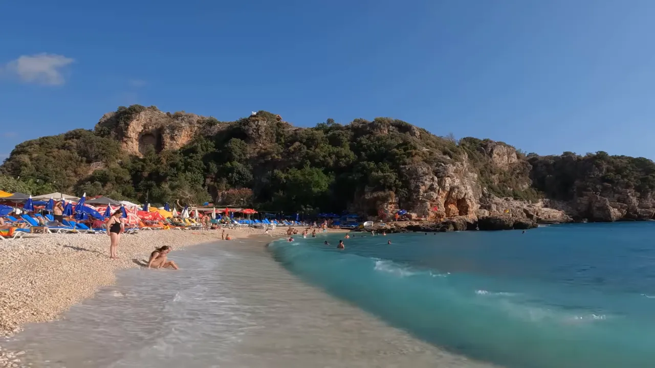 Büyükçakıl Plajı çakıl taşlı sahil, berrak turkuaz su ve kayalık arka plan, net ve yüksek kaliteli görüntü