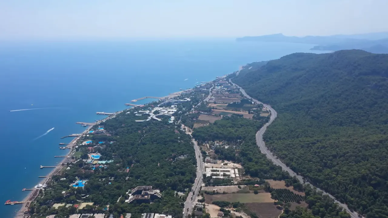 Beldibi kuşbakışı net drone çekimi — kıyı, iskeleler ve ormanlık yol
