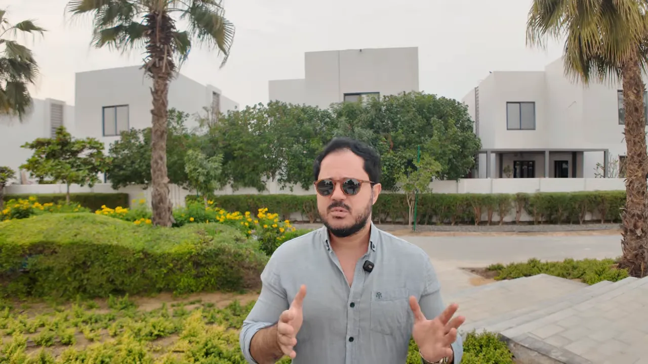 Dubai&rsquo;de şirket kurma maliyeti hakkında konuşan kişi, avluda modern bina arka planı