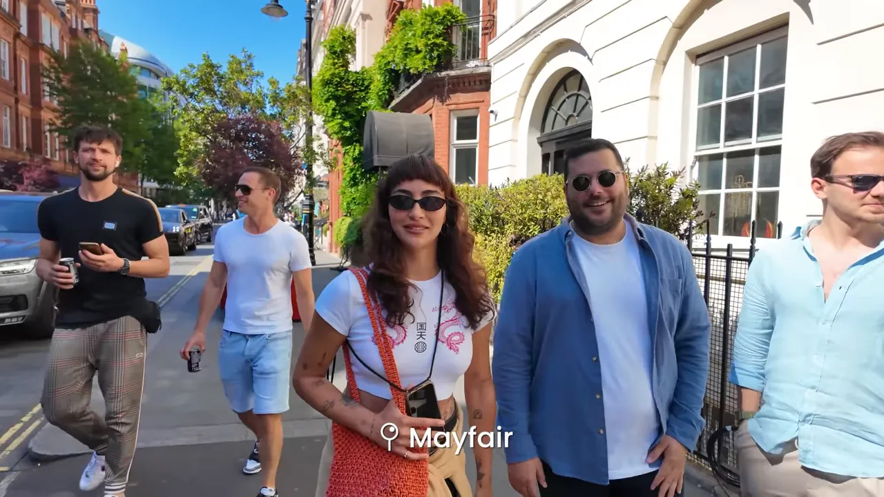 Ekranda 'Mayfair' yazısı ile birlikte Mayfair sokakta y&uuml;r&uuml;yen insanlar; merkezi ve pahalı bir semt vurgusu.