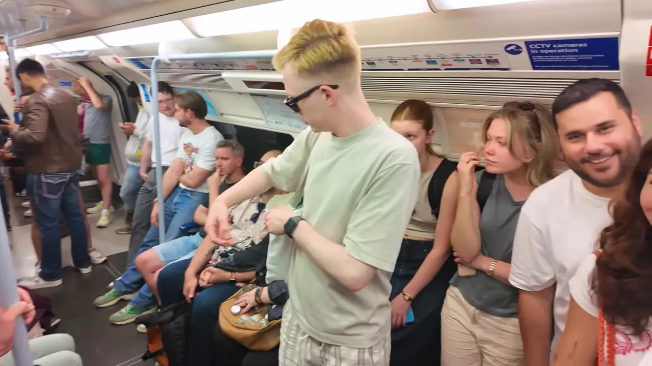 Londra metrosu i&ccedil;i, ayakta duran ve oturan yolcuların olduğu kalabalık vagon.