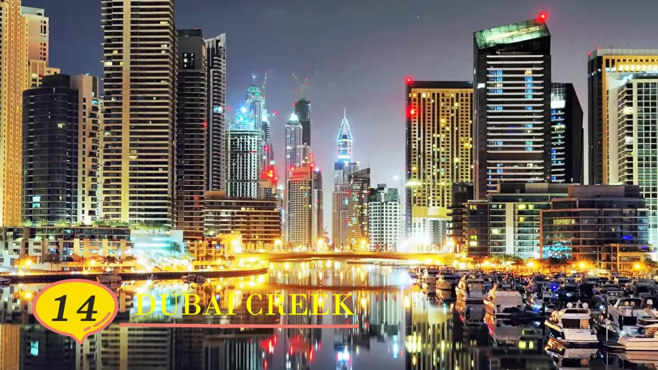 Night view of Dubai Creek with yachts, calm reflective water and lit high‑rise buildings (text overlay reading 'Dubai Creek')