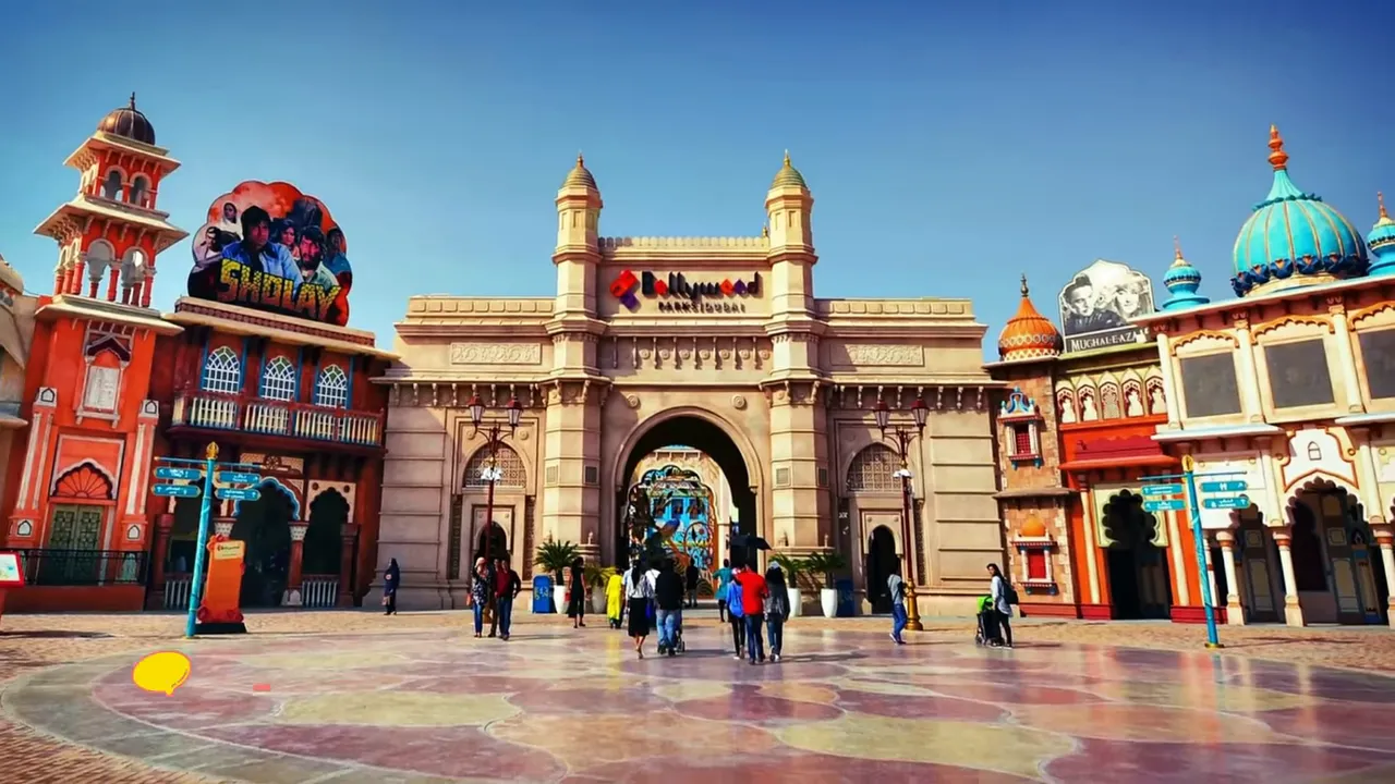 Wide, unobstructed view of Bollywood Parks Dubai entrance with ornate archway and visitors walking toward the park