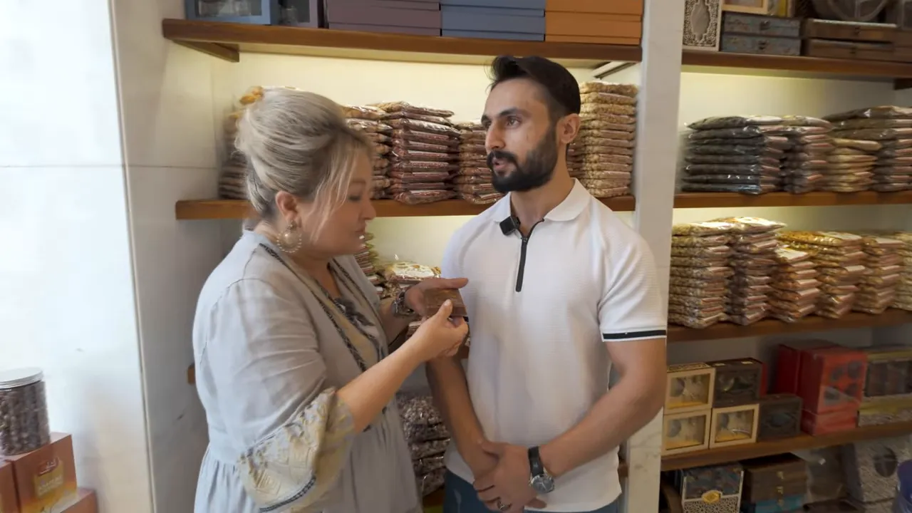 Mağazada k&uuml;nefe dolgulu Dubai &ccedil;ikolatasını g&ouml;steren kişi ve satıcı