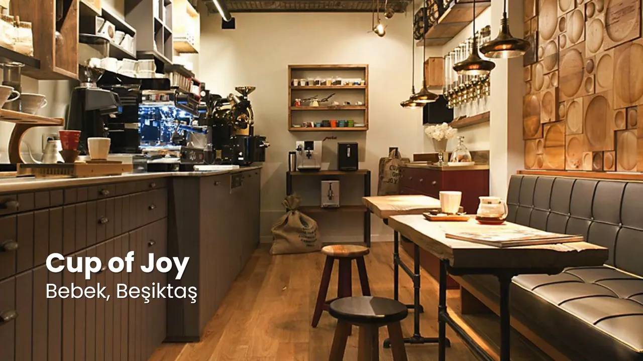 Inviting interior of Cup of Joy caf&eacute; in Bebek with wooden tables, bench seating, pendant lights and coffee equipment.