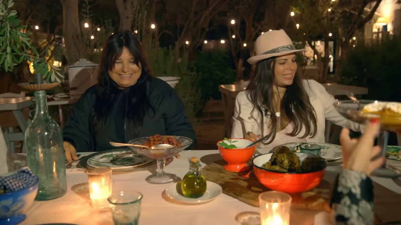 Candlelit outdoor dinner table in Alaçatı with shared Aegean dishes, olive oil bottle, and diners