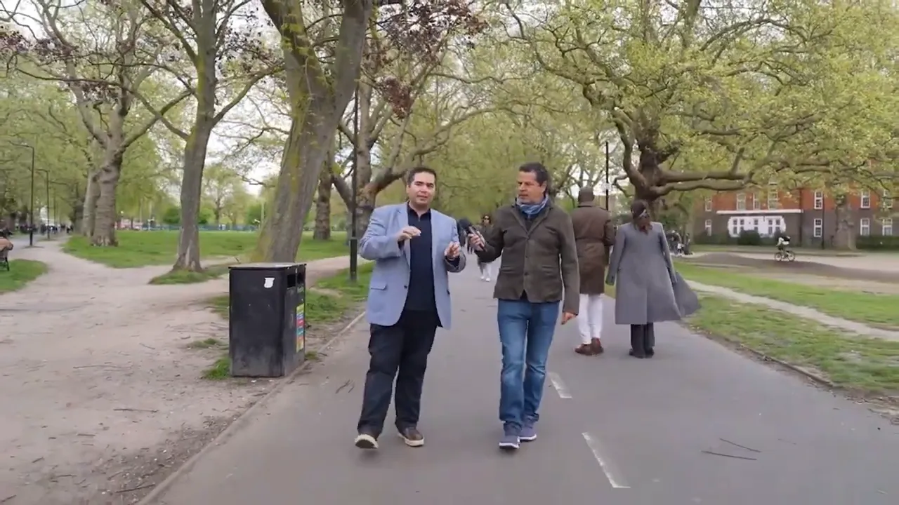 İki sunucunun London Fields parkında y&uuml;r&uuml;yerek r&ouml;portaj yaptığı net ve dengeli kare