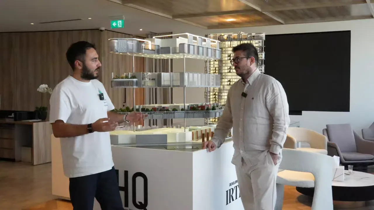 Ofis maketi merkezde, iki kişi mimari ve lokasyon avantajlarını tartışıyor.