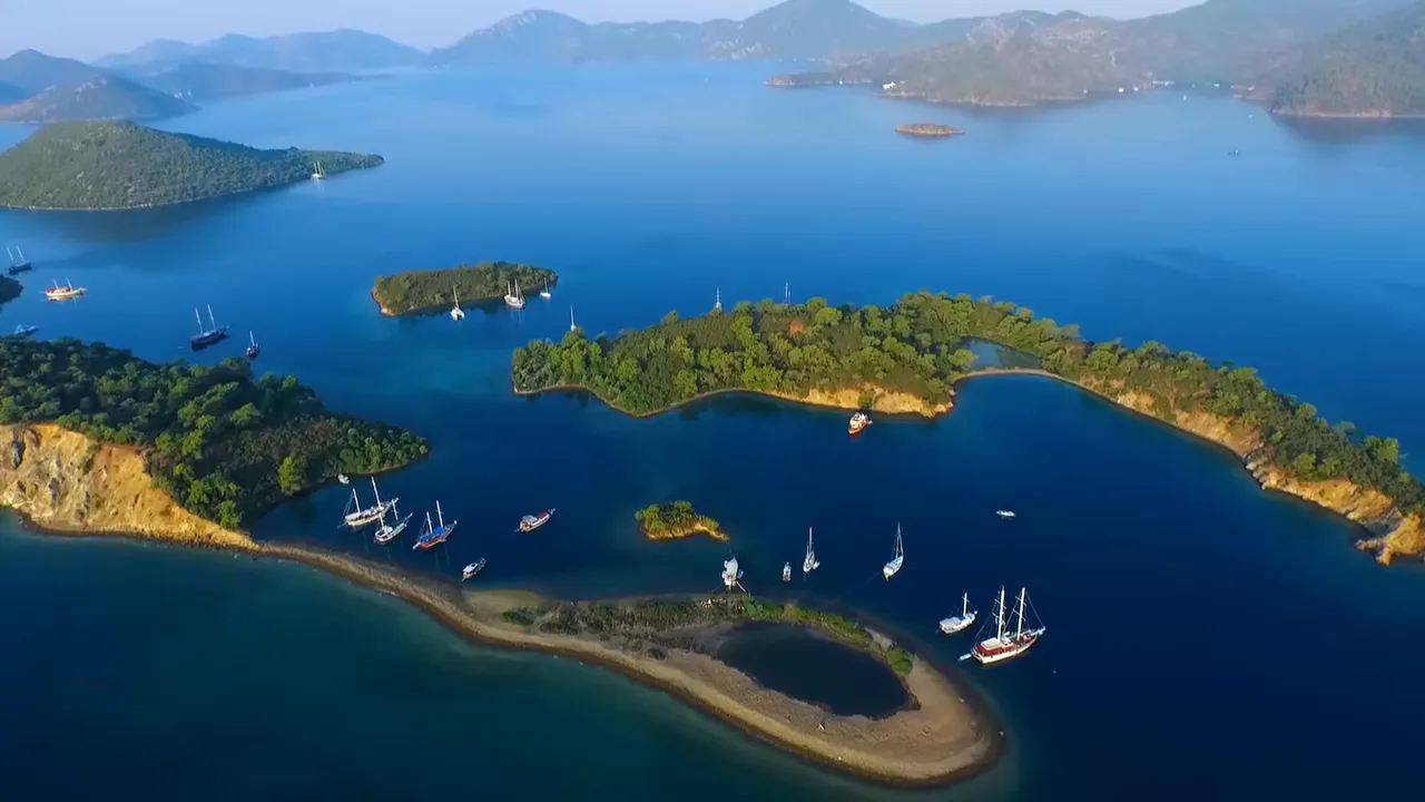 Aerial shot of turquoise sea, small islands and sailboats anchored near the coast