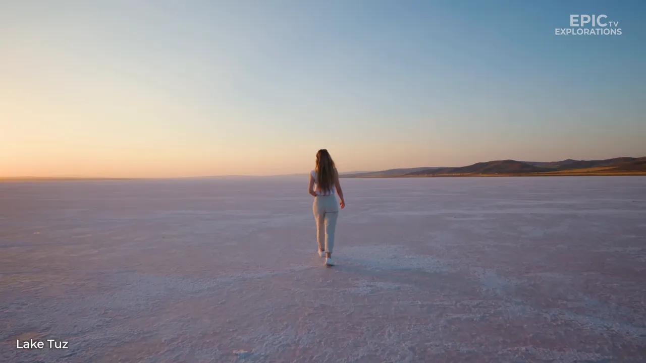 Person walking across Lake Tuz salt plain at sunset with wide horizon