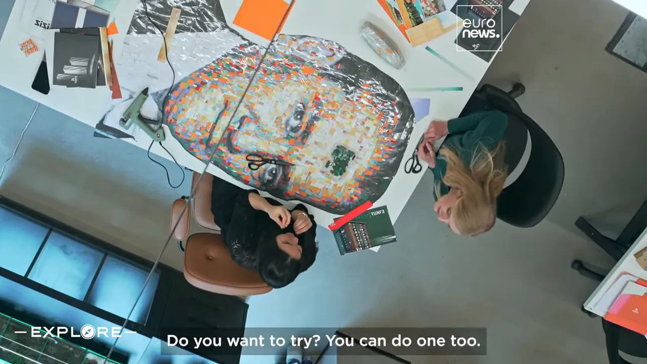 Top-down view of a colorful upcycled portrait on a table with scissors, glue gun and collage materials.