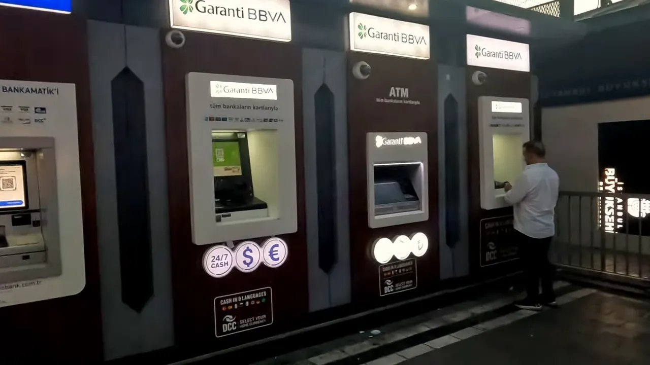 Row of Garanti BBVA ATMs in Turkey with a person using one of the machines
