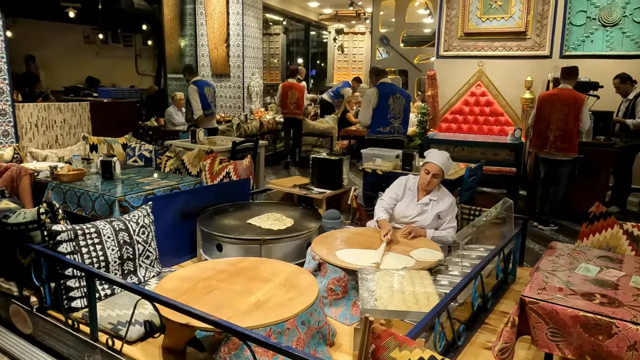 Restaurant interior with chef rolling flatbread and diners inside