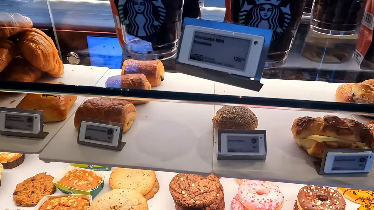 Starbucks pastry display case with croissants, cookies, donuts and price tags