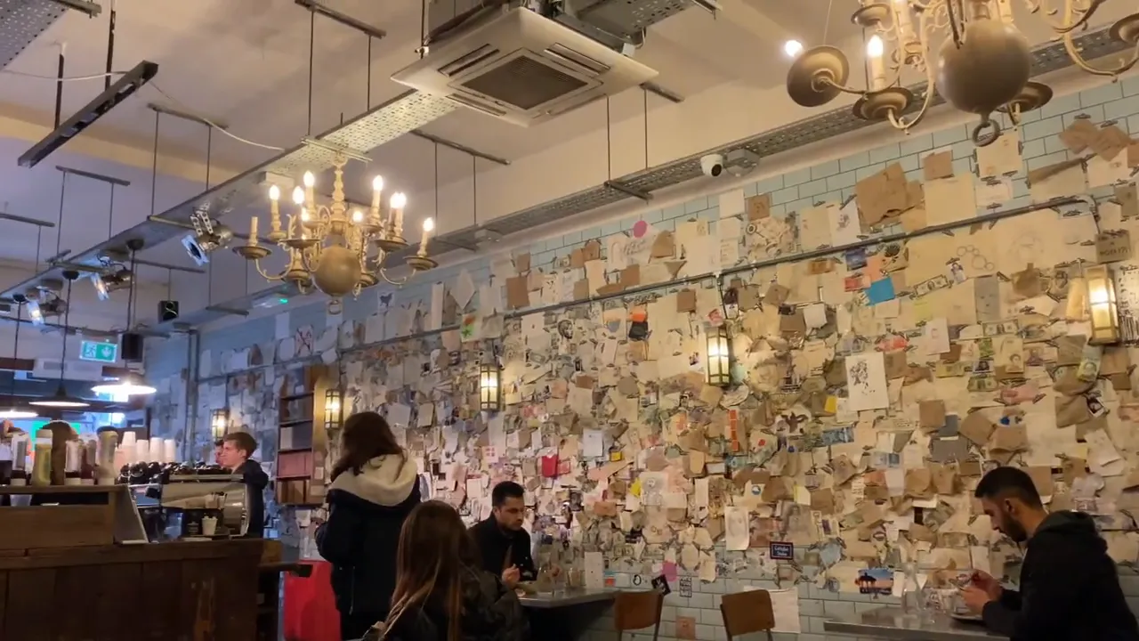 Cable Cafe&rsquo;de duvarda asılı kartlar, avize ve oturma alanlarıyla i&ccedil; mekan g&ouml;r&uuml;n&uuml;m&uuml;