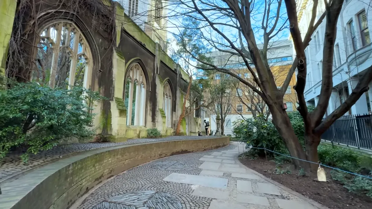 Curved cobbled path and ruined church walls with trees at St Dunstan in the East