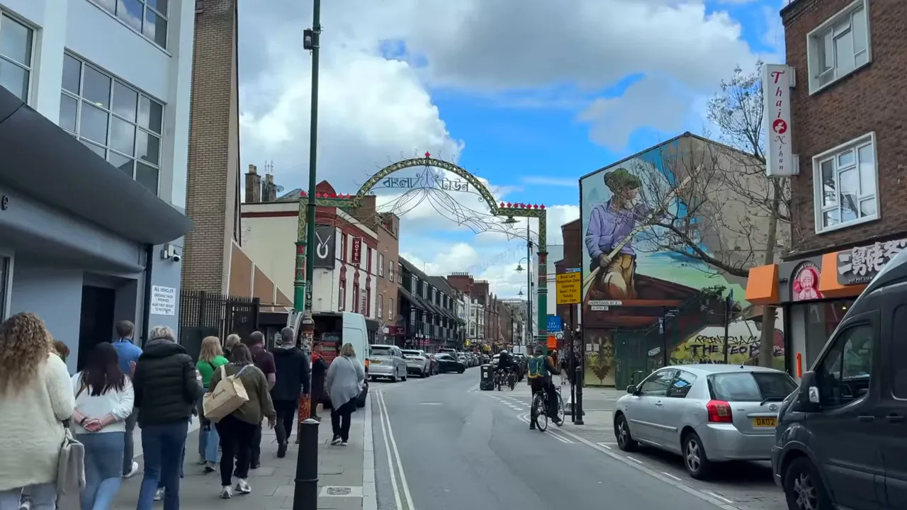 Brick Lane street with entrance arch, mural and pedestrians