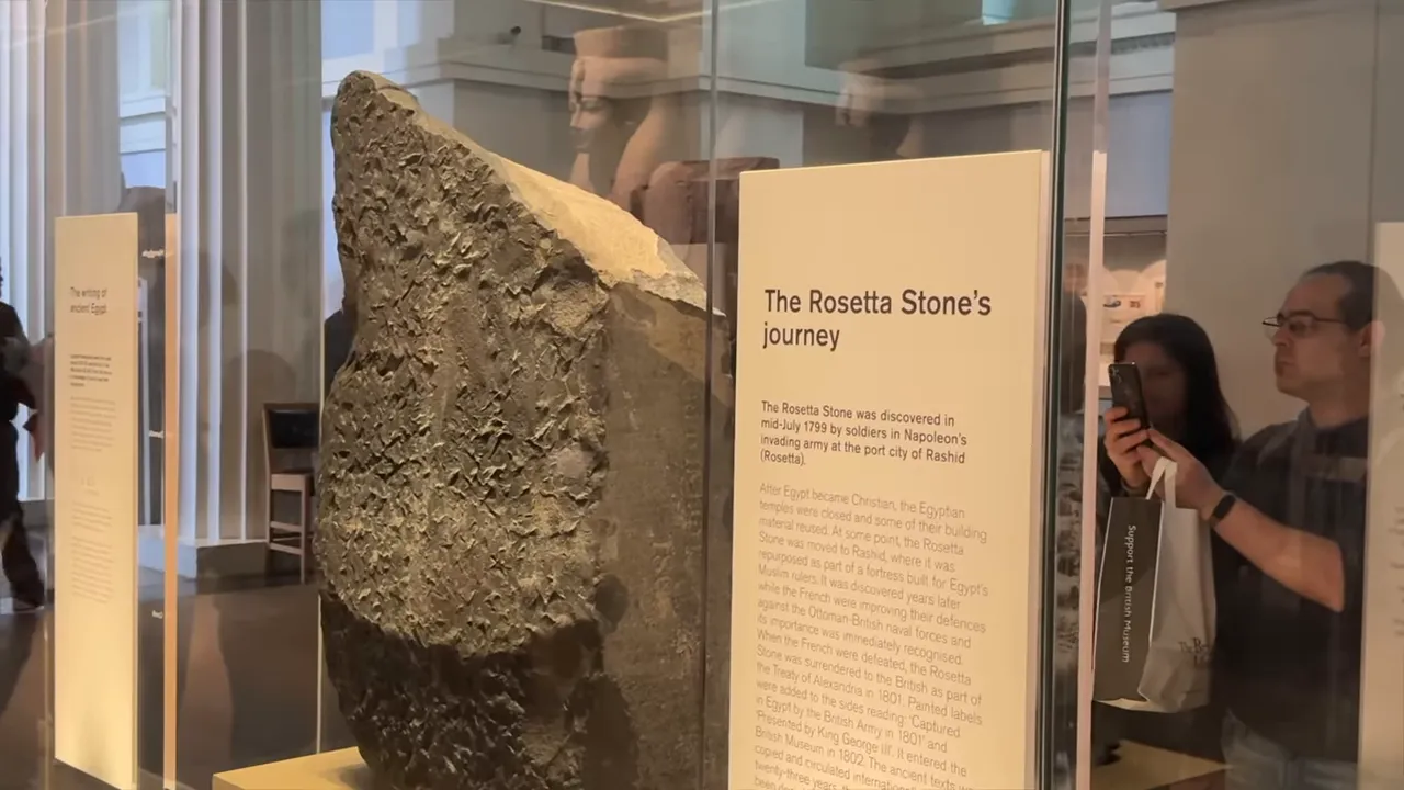 The Rosetta Stone displayed behind glass with an explanatory sign at the British Museum