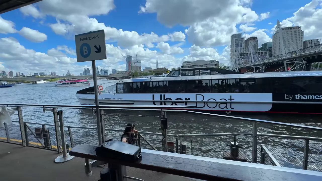 Uber Boat by Thames Clippers moored at a boarding point on the Thames with London skyline and clear 'Boarding point B' sign.