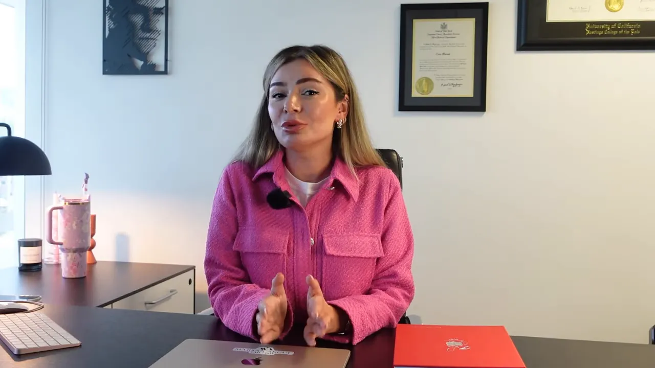 Masa başında oturan konuşmacı, Green Card başvurusu hakkında kapanış notları anlatıyor; temiz ve dikkat dağıtıcı &ouml;ğesiz kare.