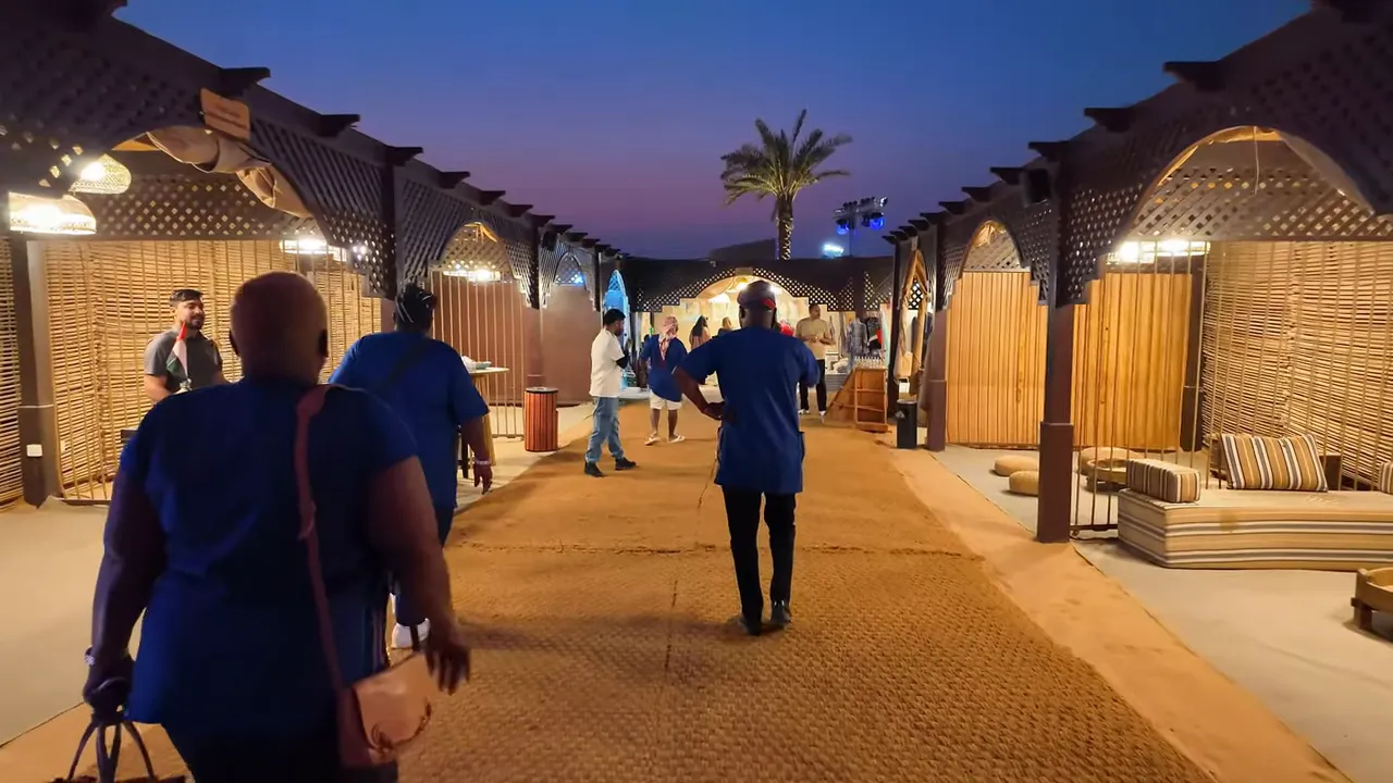 Akşam aydınlatmasında &ccedil;&ouml;l kampı ana y&uuml;r&uuml;y&uuml;ş yolu, yanlardaki stantlar ve oturma minderleri.