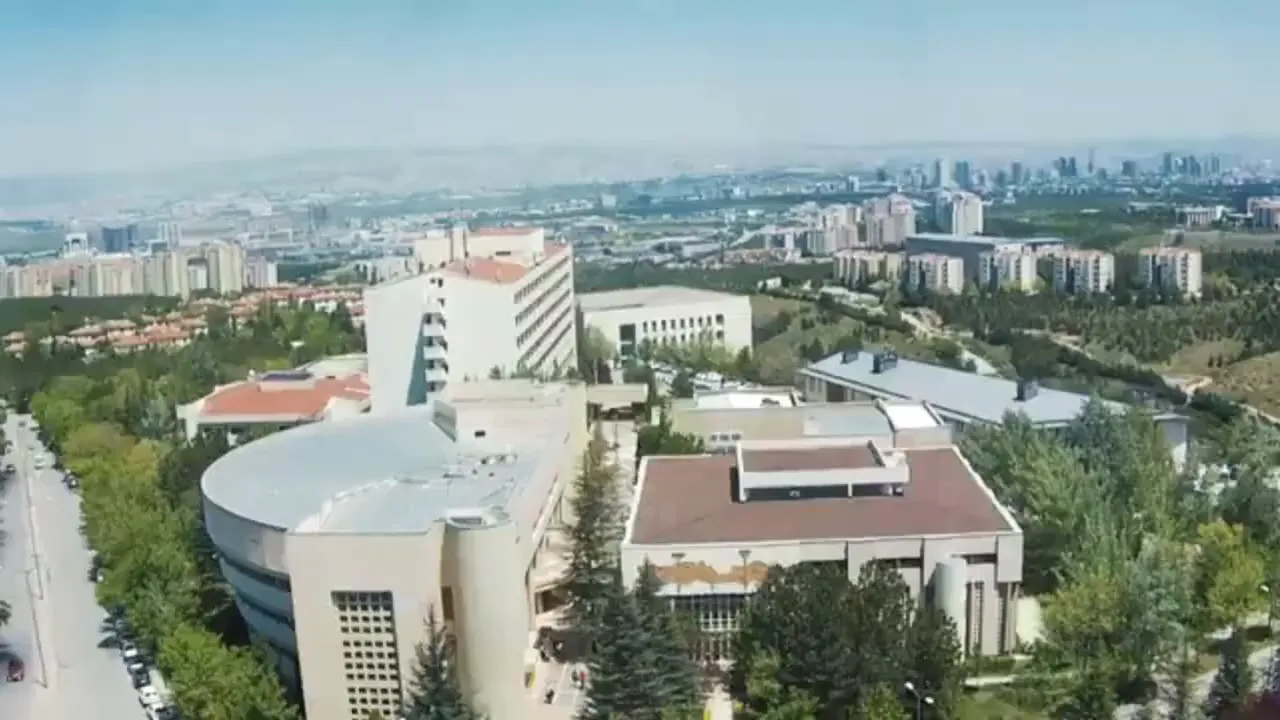 Aerial shot of a university campus with academic buildings, trees and distant city skyline