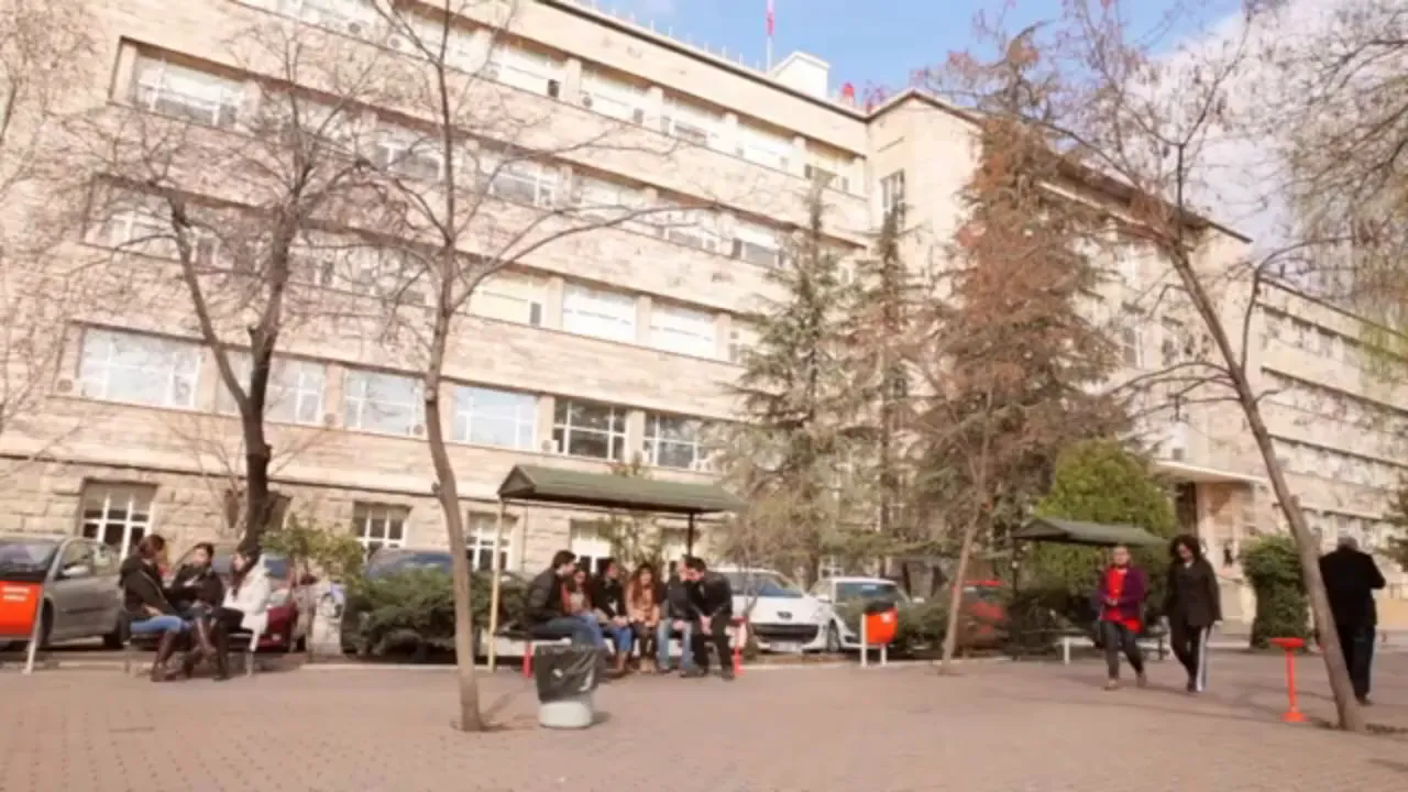 Exterior of a university building with students sitting on benches in the courtyard