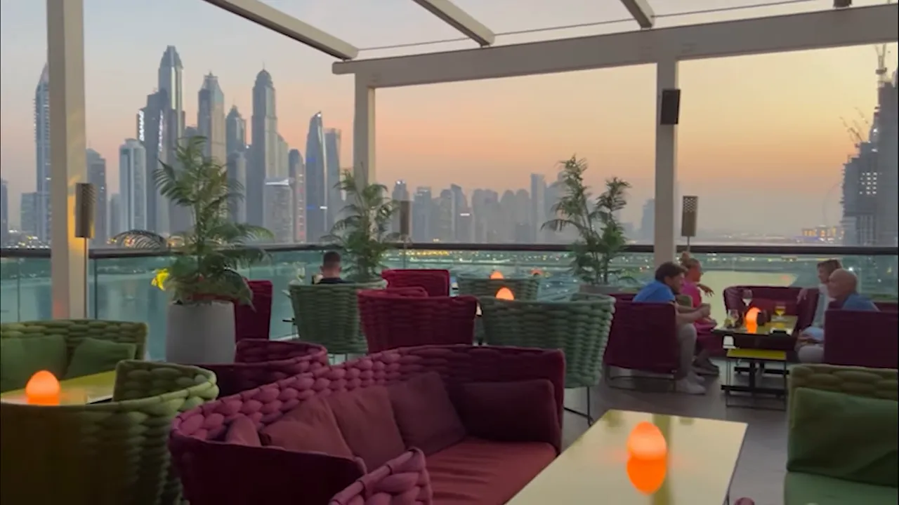 Rooftop lounge with plush seating at sunset overlooking the Dubai skyline