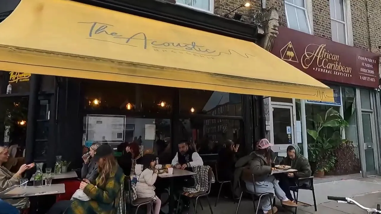 The Acoustic kafe sarı tentesi ve dışarıda oturan m&uuml;şteriler, Stoke Newington.