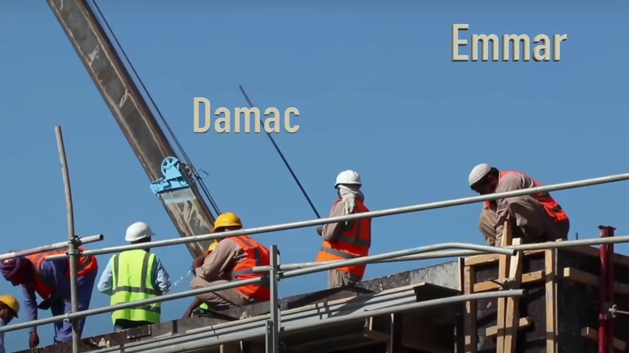 Construction workers on scaffold with overlaid developer names 'Damac' and 'Emaar' against a clear blue sky