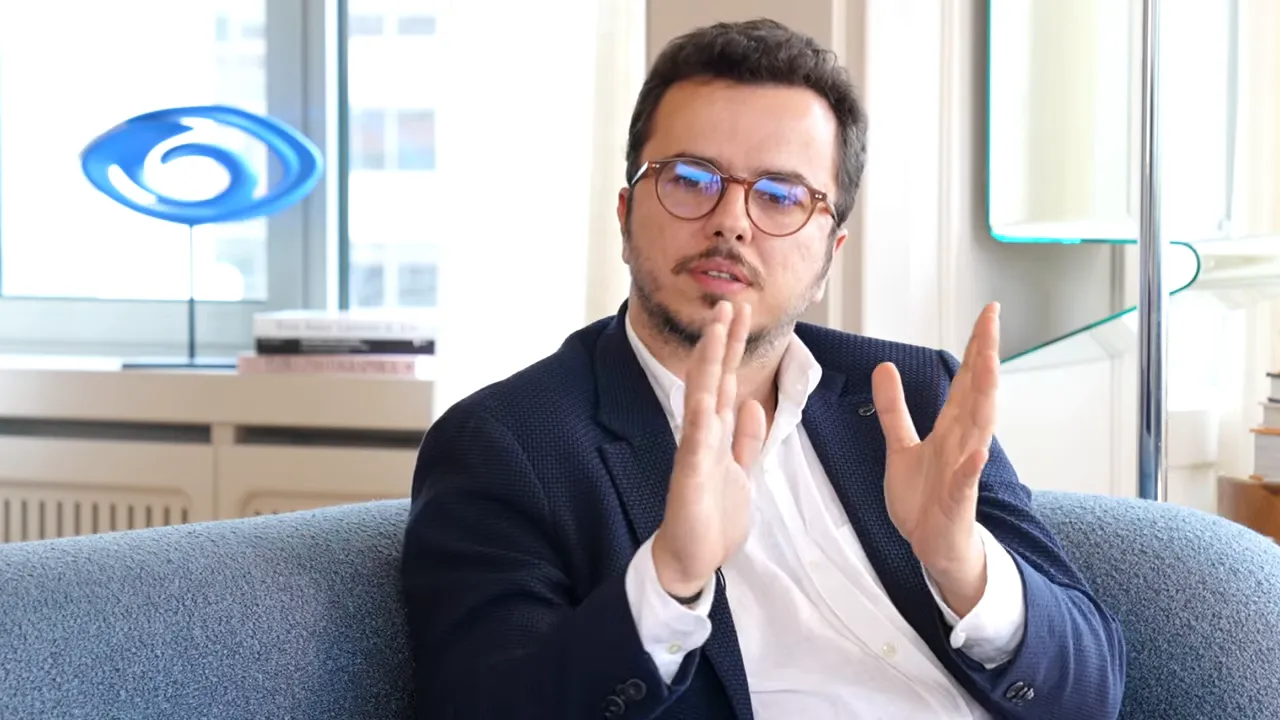 Konuşan adam ellerini karşılaştırma yapar gibi tutuyor, ofis ortamı