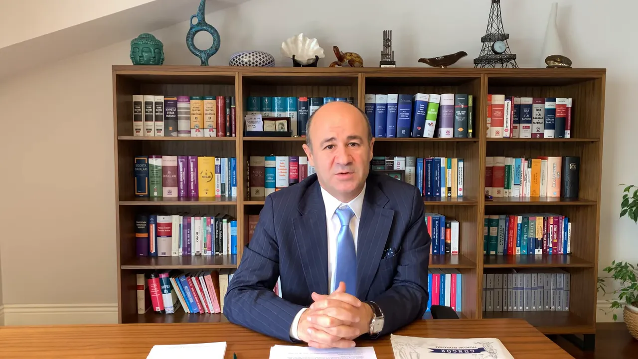 Kitaplıklı arka planda kameraya doğrudan bakan sunucu, profesyonel duruş ve net g&ouml;r&uuml;n&uuml;rl&uuml;k.