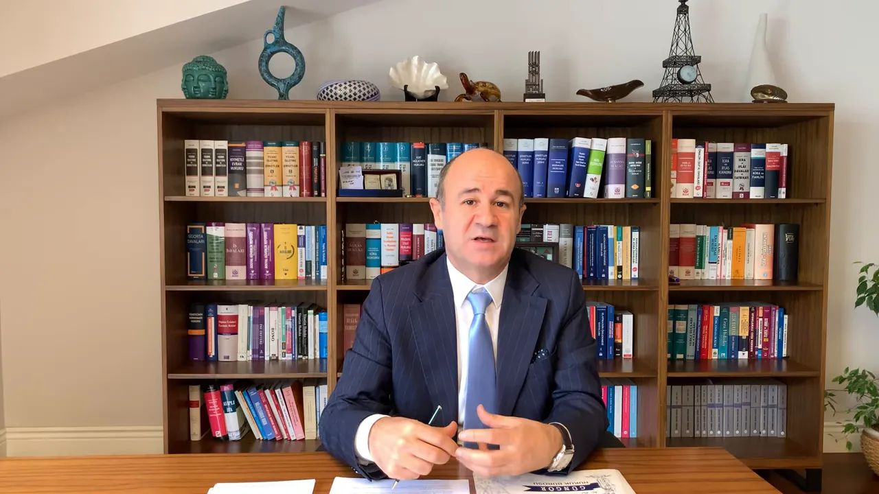 Ellerini kullanarak a&ccedil;ıklama yapan konuşmacı, arkasında hukuk kitaplarıyla ofis