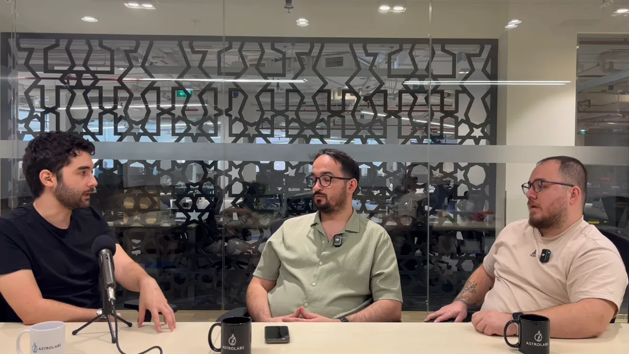 &Uuml;&ccedil; konuşmacı toplantı masasında, camlı ofis arkasıyla net ve dengeli kompozisyon.