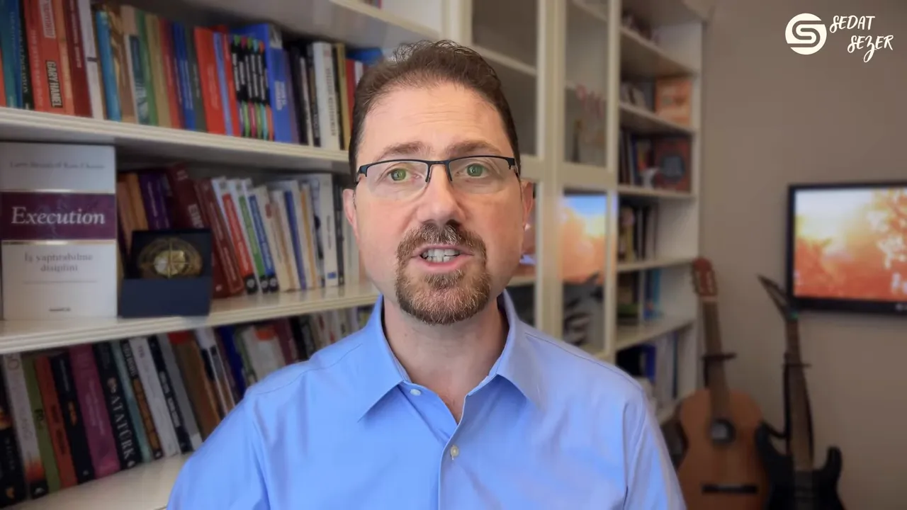 Konuşmacı mavi g&ouml;mlekle net ve sabit &ccedil;er&ccedil;evede; yapay zeka ve veri entegrasyonu konusunu a&ccedil;ıklıyor, arka planda kitaplık ve gitarlar.