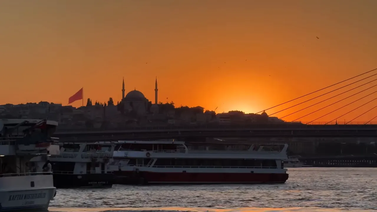 Sunset over the Bosphorus with boats in the foreground and mosque silhouette on the skyline