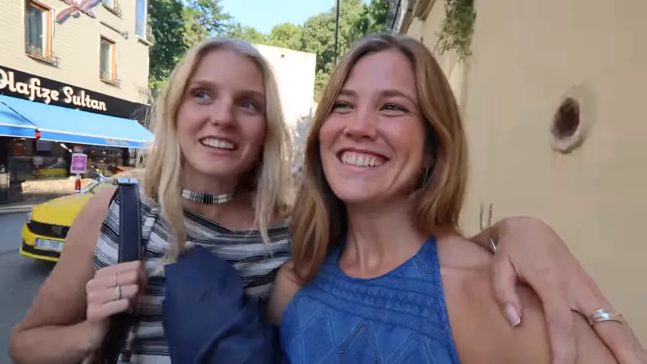 Two smiling friends on an Istanbul street in front of shops, about to enter the Egyptian Bazaar area.