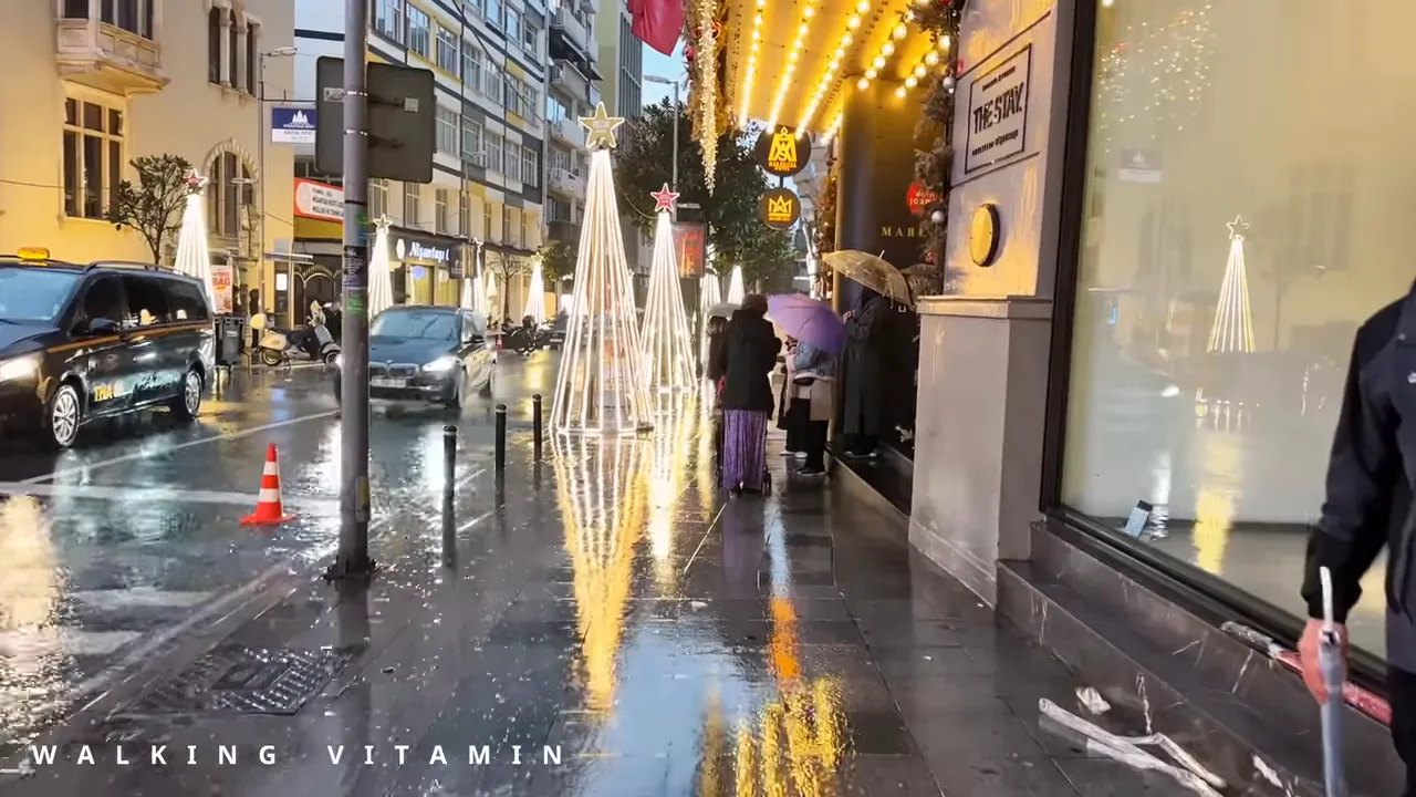 Nisantasi wet pavement reflecting illuminated Christmas cone lights and shopfronts, with umbrellas and pedestrians in the background