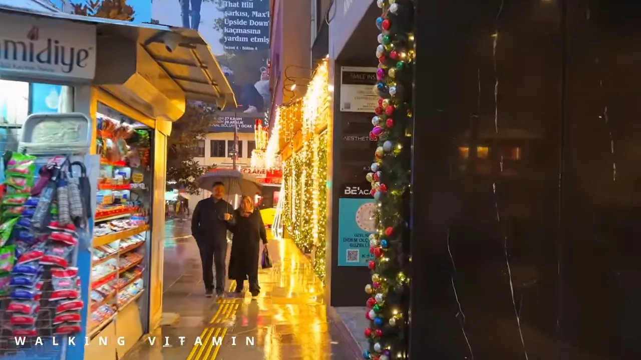 Couple walking under an umbrella on a wet Nisantasi street lined with illuminated holiday garlands and shop stalls.