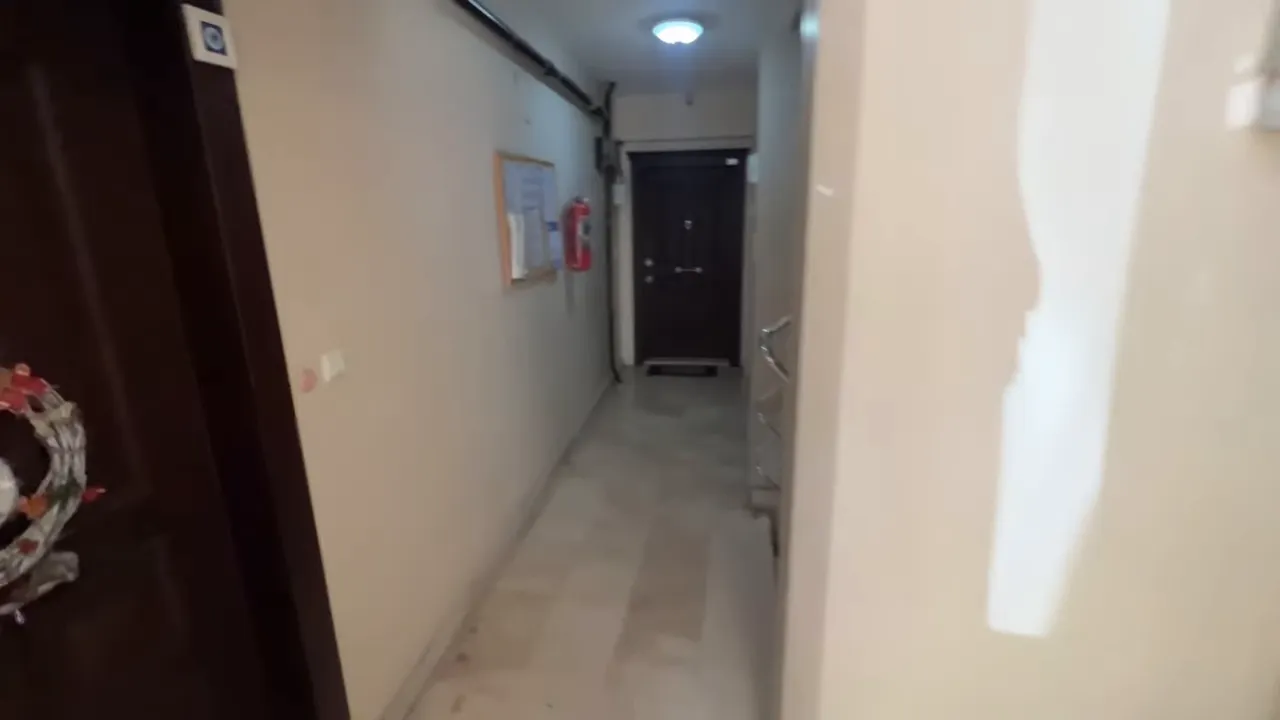 Narrow apartment building corridor with front doors and tiled floor