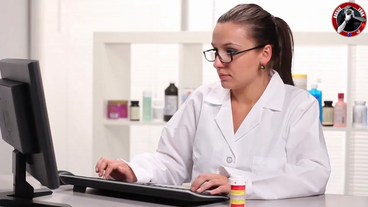 Beyaz &ouml;nl&uuml;k giymiş sağlık &ccedil;alışanı bilgisayarda re&ccedil;ete bilgilerini giriyor; masada ila&ccedil; şişesi ve klavye net şekilde g&ouml;r&uuml;n&uuml;r.