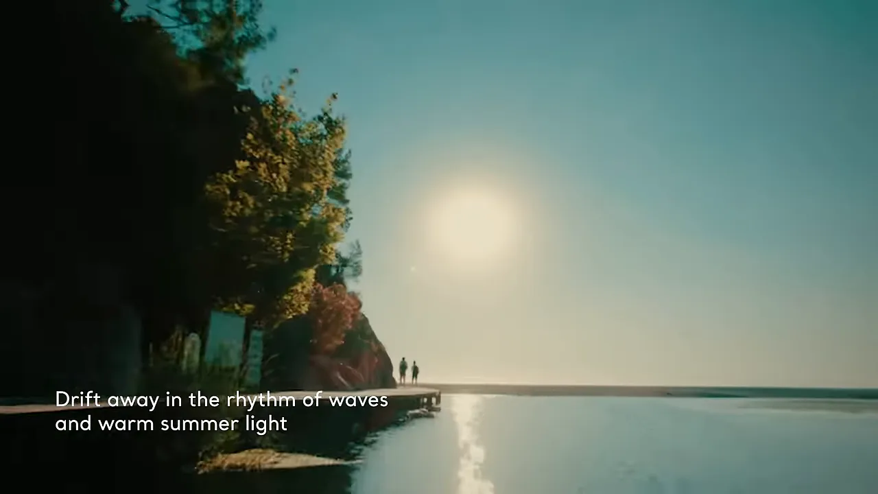 sunlit pier with two people walking and calm reflective water at the shoreline