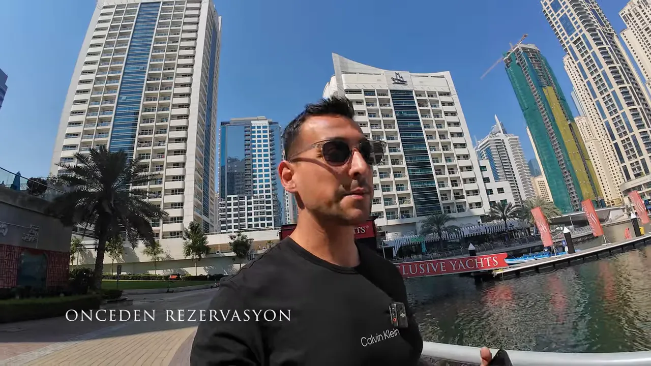 Sunucu Dubai marinasında y&uuml;r&uuml;rken ekranda '&Ouml;NCEDEN REZERVASYON' yazısı