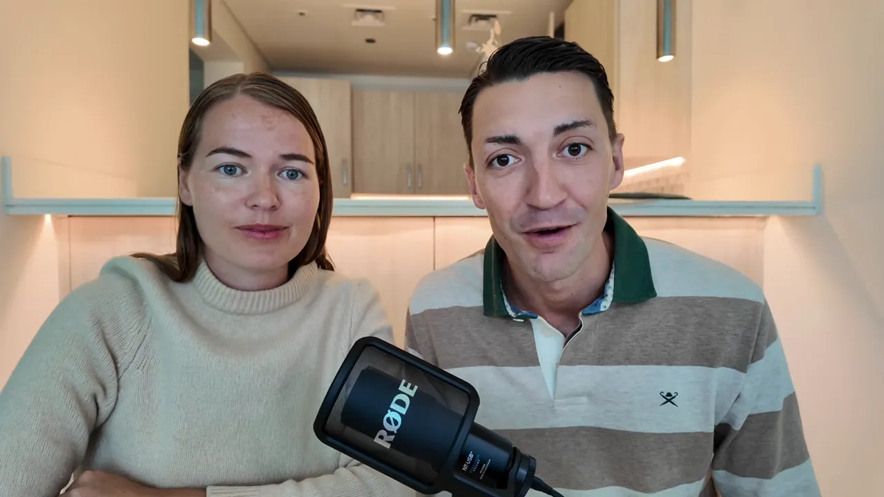 Two presenters facing the camera in a clean indoor setting with a microphone to the front-right.