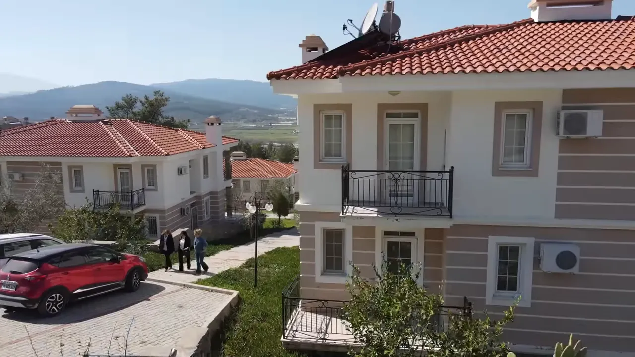 Coastal Turkish villas with red tiled roofs, balconies and parked cars