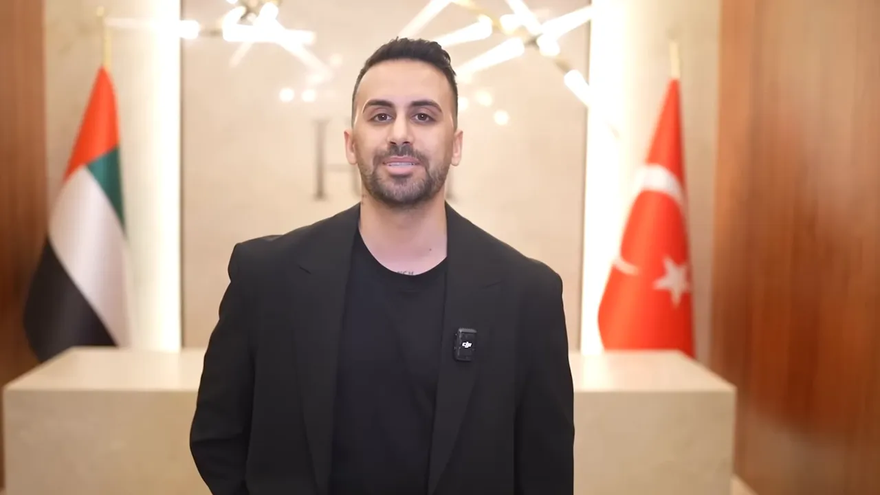 Ofis &ouml;n&uuml;nde duran sunucu, iki &uuml;lkeden bayraklar arka planda net g&ouml;r&uuml;n&uuml;yor